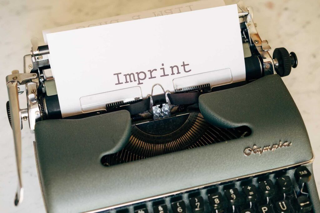 Schreibmaschine mit einem Papierstreifen, auf dem das Wort ‚Imprint‘ steht